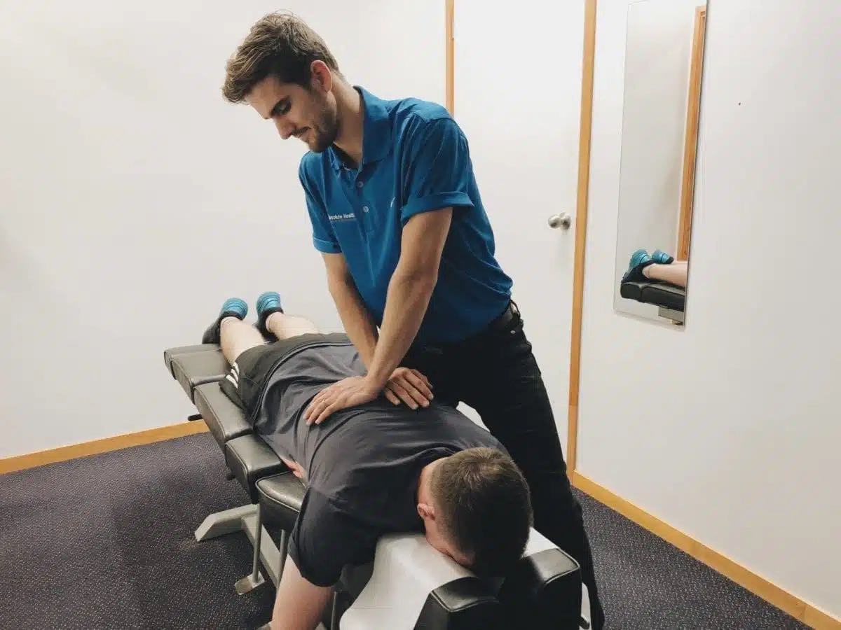Chiropractor examining patient's back on treatment table, Absolute Health physiotherapy services.
