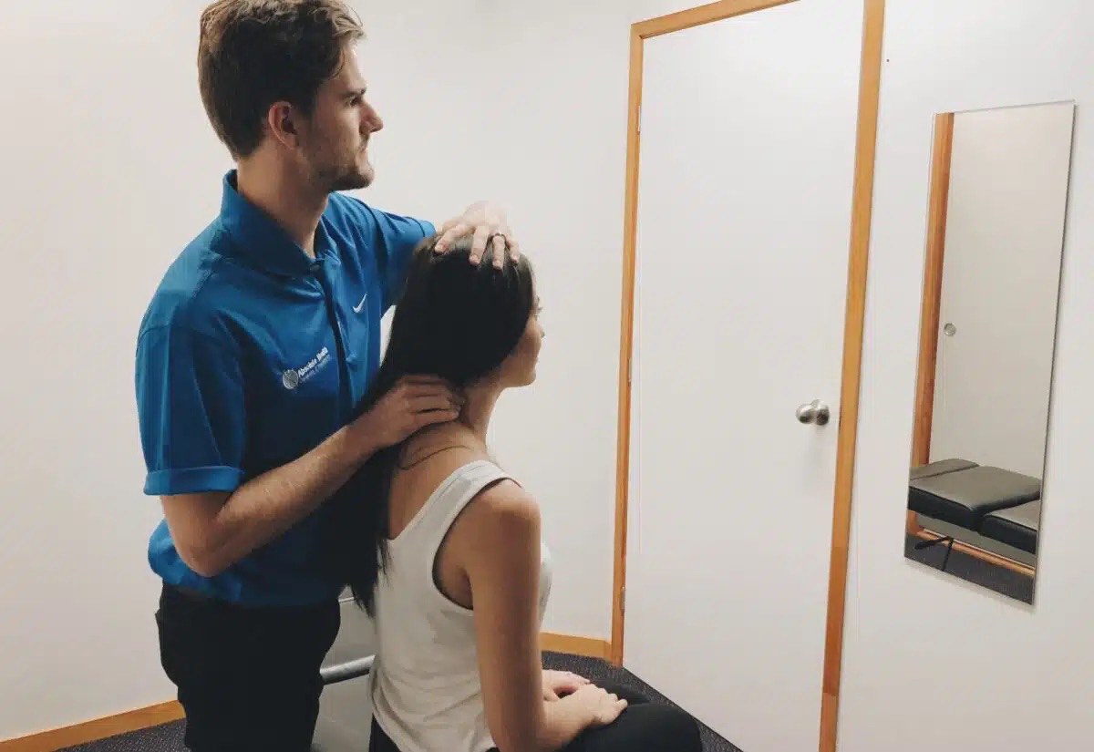 Chiropractor assessing patient's neck in Absolute Health Mooloolaba clinic.