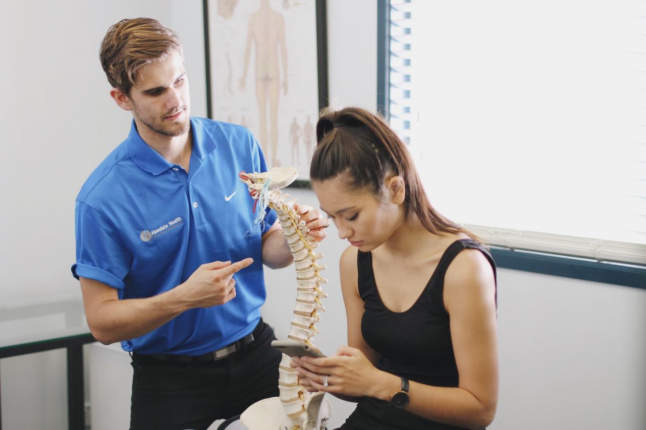 Chiropractor explaining disc anatomy to patient using spine model at Absolute Health