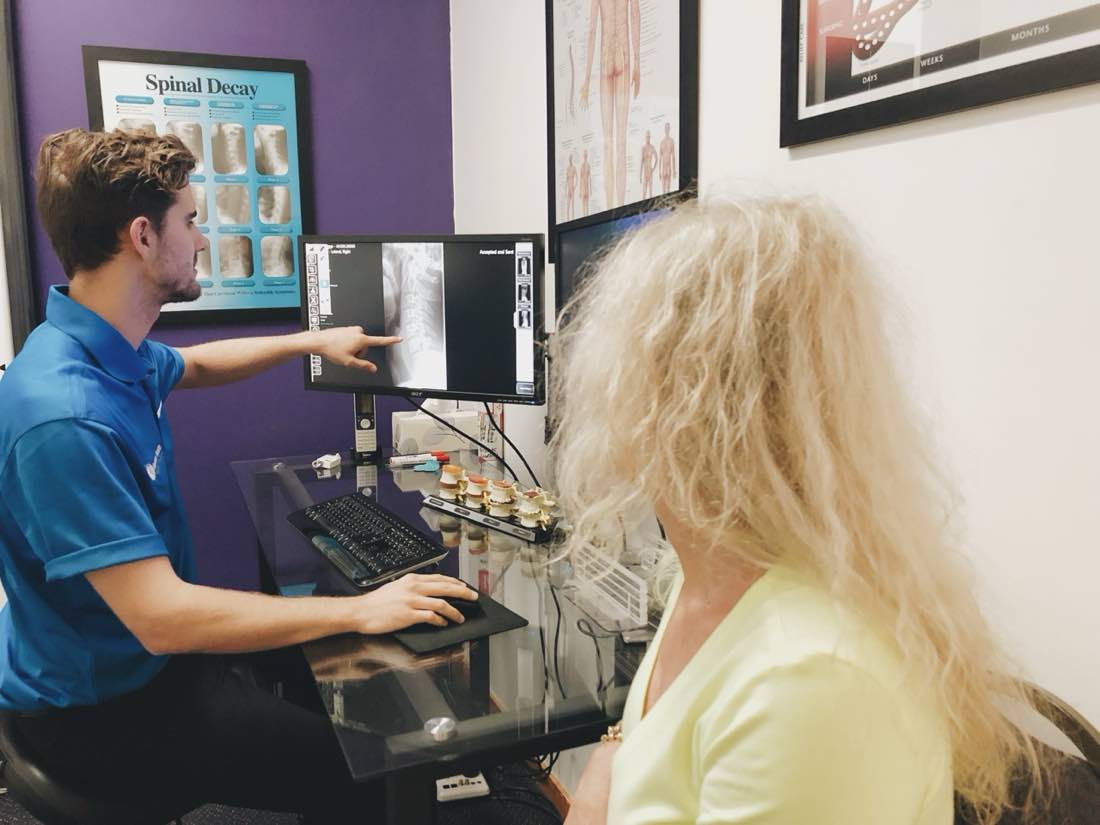 Absolute Health clinic: doctor explaining full-spine digital X-ray to patient.